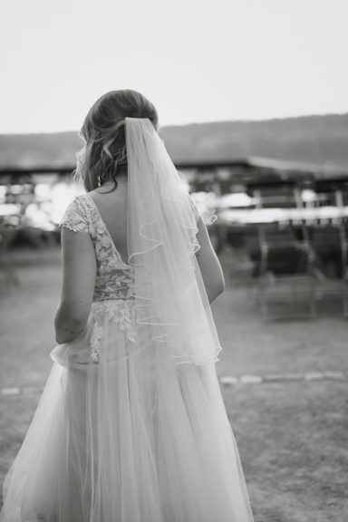 Braut von hinten in einem weißen Kleid mit Schleier, Spaziergang im Freien.