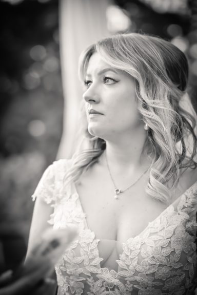 Frau mit welligem Haar in einem eleganten Kleid, nachdenklicher Blick im Freien.
